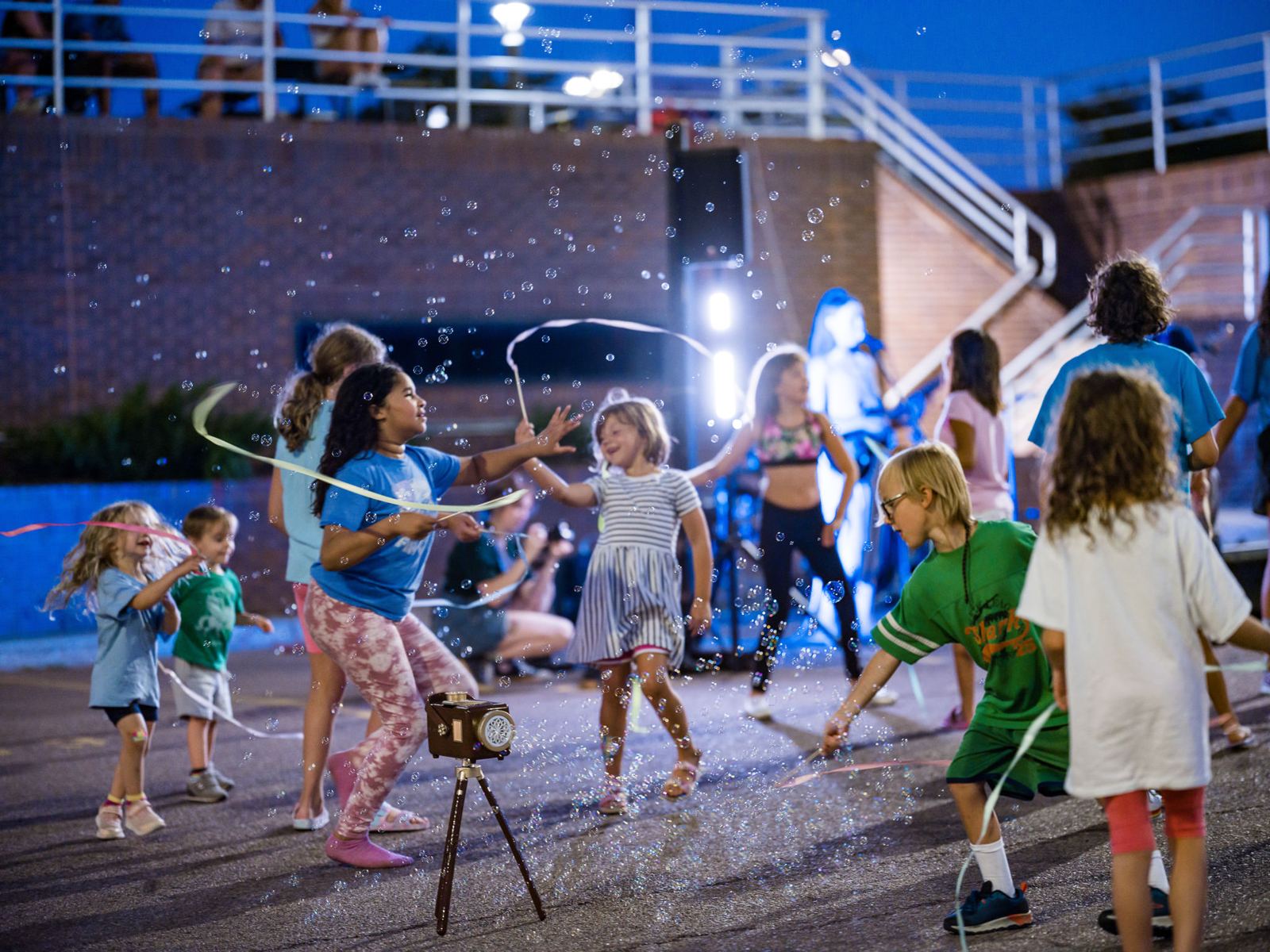 Kids dancing with ribbons and bubbles at an evening concert in Sioux Falls