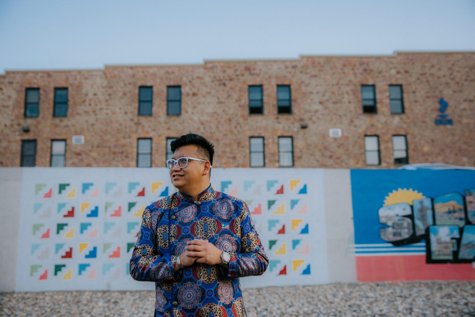 Vince in a patterned Vietnamese jacket in front of a colorful Sioux Falls mural