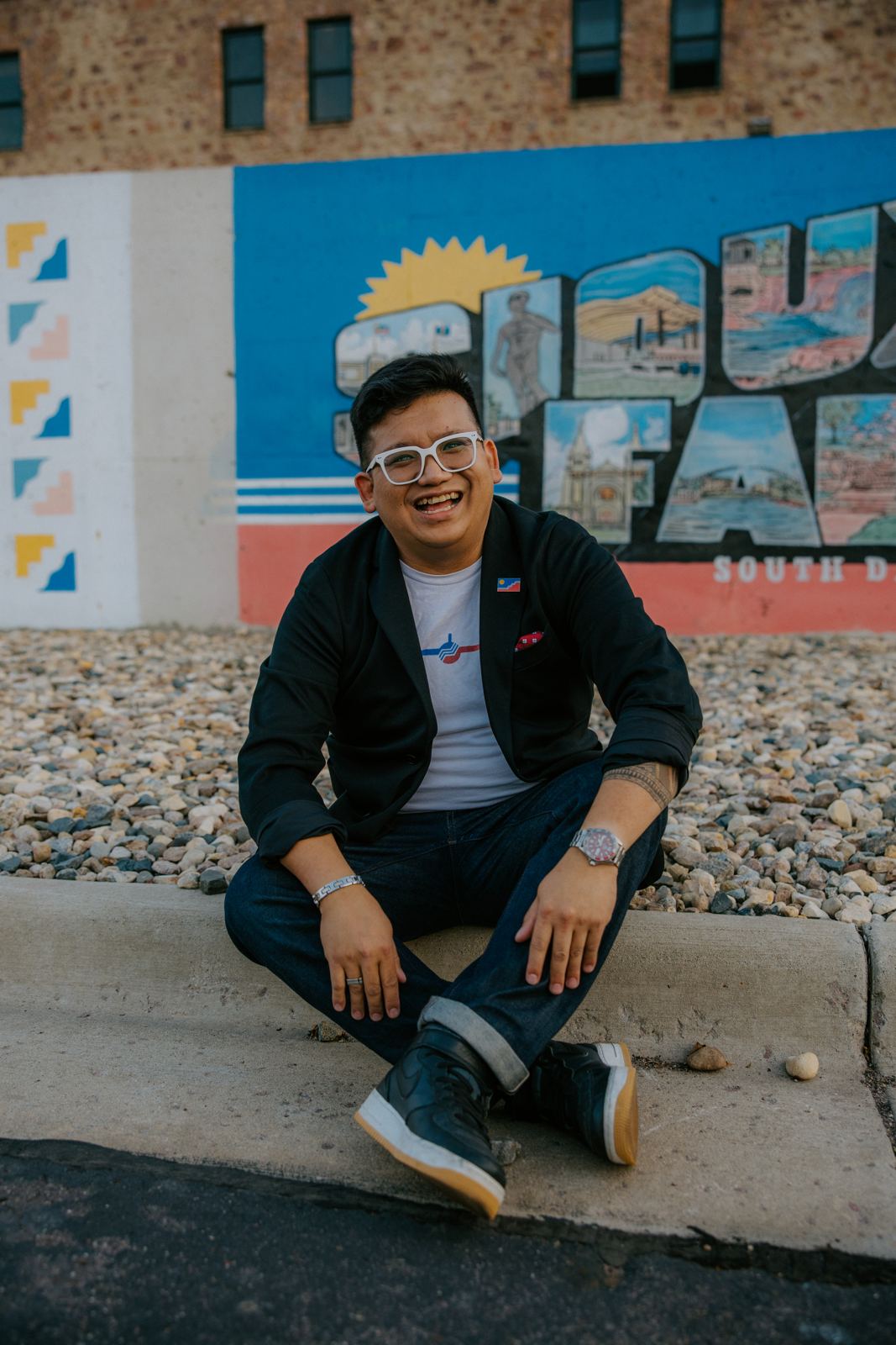 Vince laughing in front of the Greetings from Sioux Falls mural
