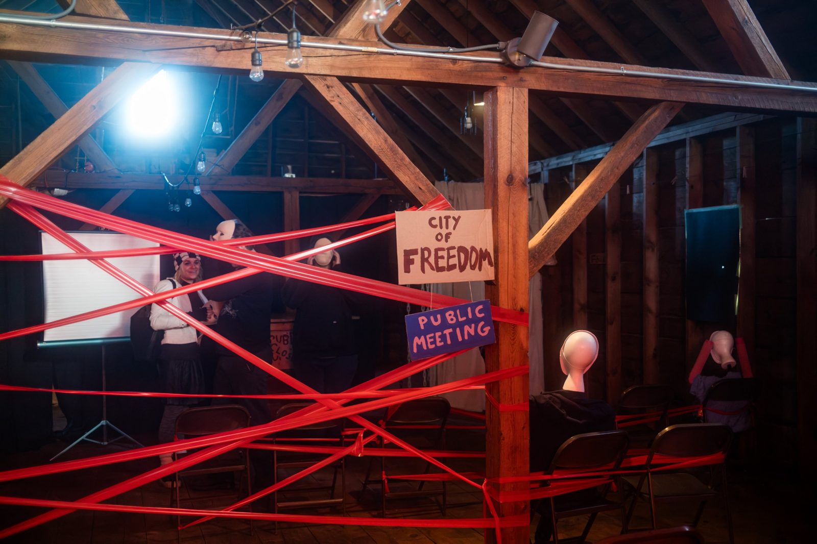 Red tape crisscrossing a staged public meeting under a sign reading "City of Freedom"