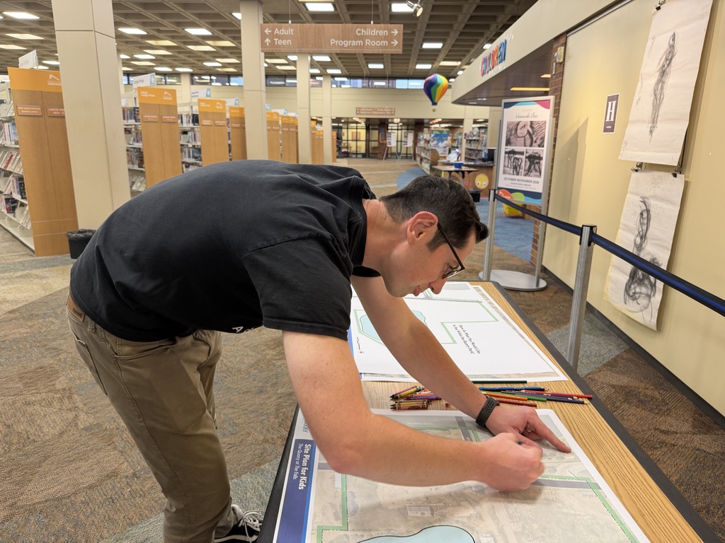 A neighbor draws on a site plan of The Quarry with crayons