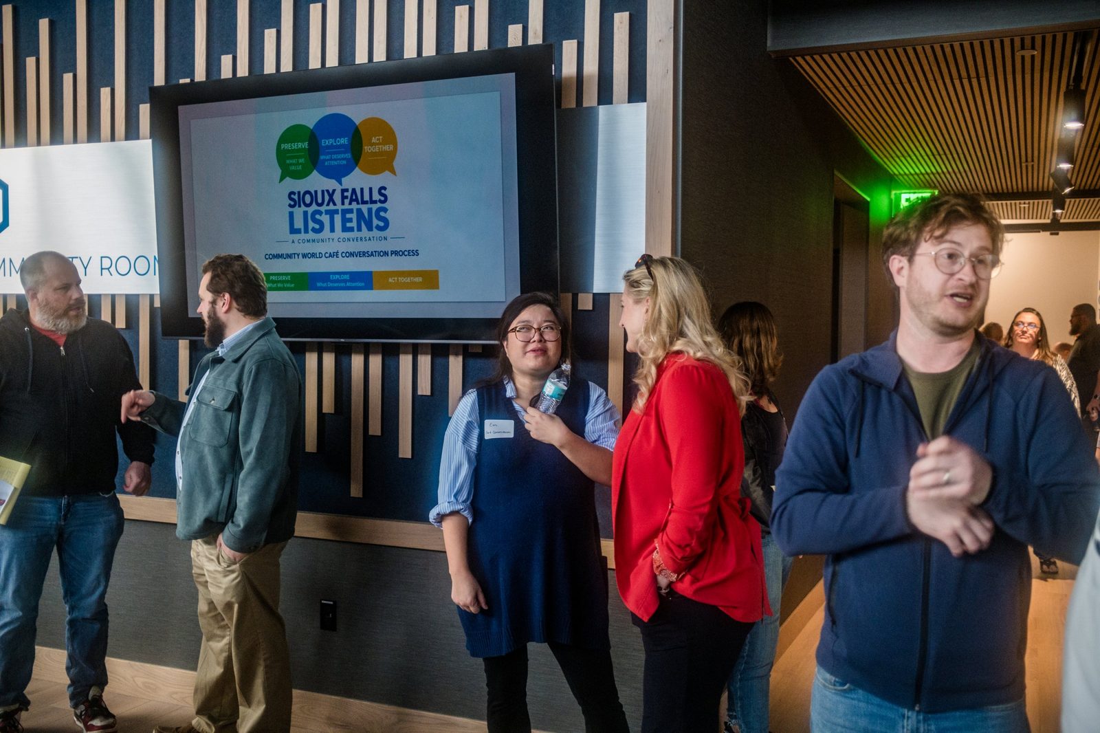 A speaker at the microphone with the night's conversation guidelines on the screen, including Be Curious and Disagree With Respect