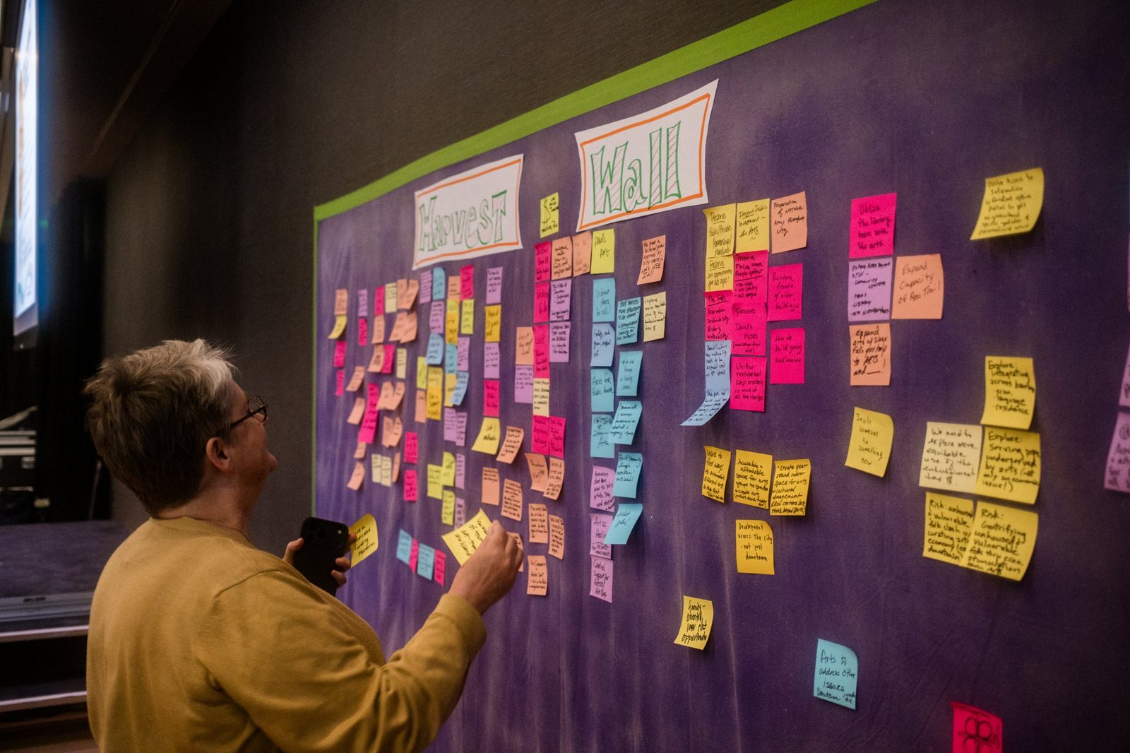 A participant reads ideas posted on sticky notes on the Harvest Wall
