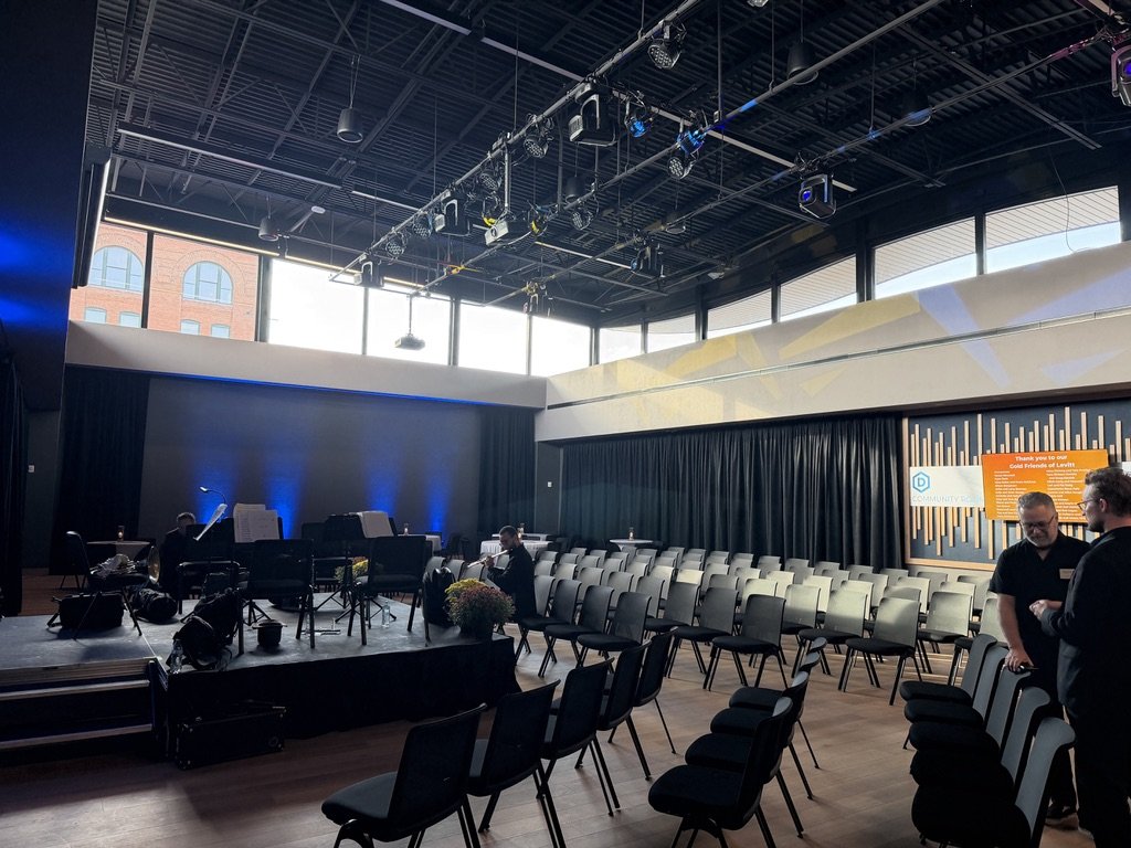 Inside the new Sweetman Atrium at Levitt at the Falls, with a stage, stage lights and rows of chairs