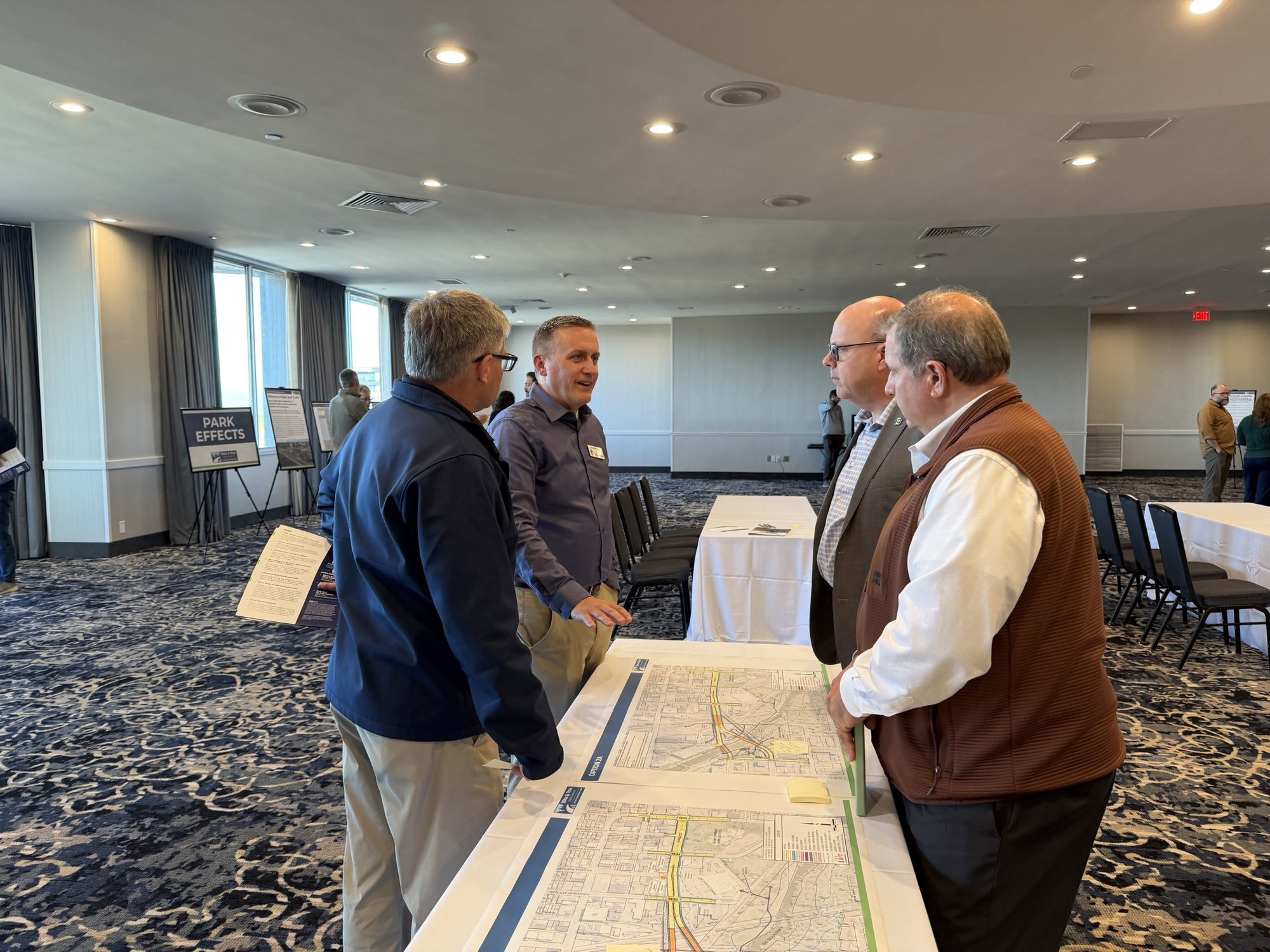 Staff from the study team talk with visitors over printed option maps